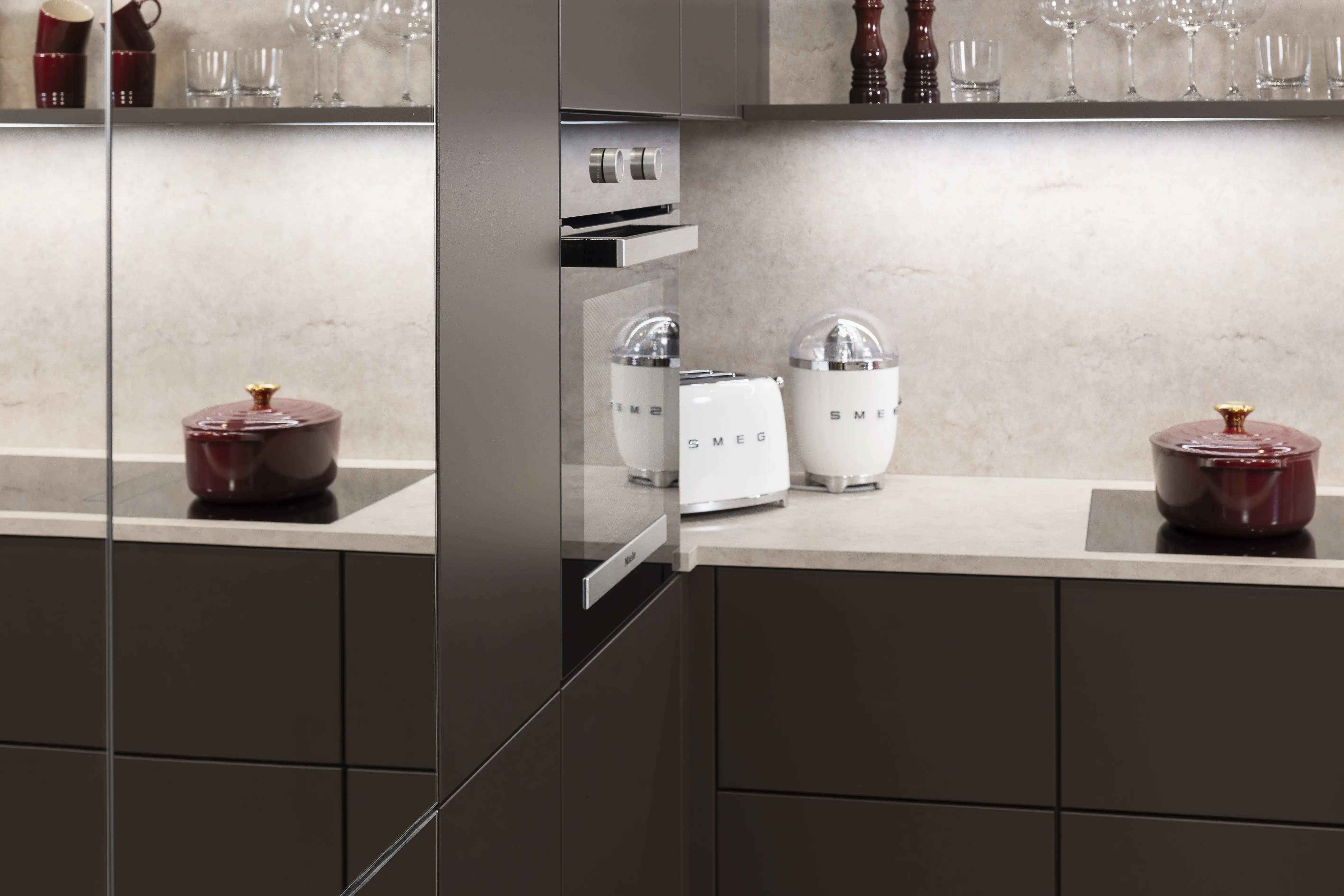 APL: Jura Beige Front: Soft Lack Sepiabraun softmatt Front: neoMirror Spiegel Korpus: Graphit Griff: PTO Geräte: Miele, Kochfeld elica Armatur: ? Spüle: Sternhagen   Features: Insellösung als Esstisch mit integrierten Unterschränken, Lichtboard über Arbeitsplatte, unterschiedliche Rastergrößen, Spielschränke für mehr Großzügigkeit, Nischenrückwand Wand hoch mit APL, ergonomischer Backofen, bedruckter Vinylboden in Steinoptik, komplette Planung PTO, Essentischlösung als zentraler Planungspunkt der Küche